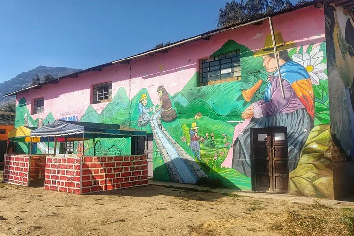 Pink building featuring colorful murals of local people and landscapes in Marcahuasi.