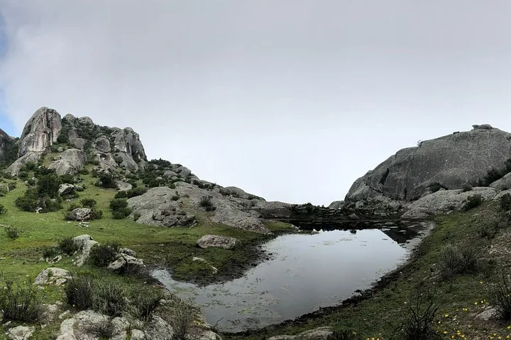 Ein kleiner Teich, der den grauen Himmel zwischen großen Felsen in Marcahuasi spiegelt