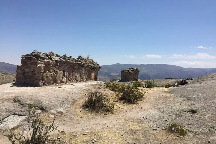 Uralte Steinruinen auf einem felsigen Plateau, im Hintergrund die Berge.